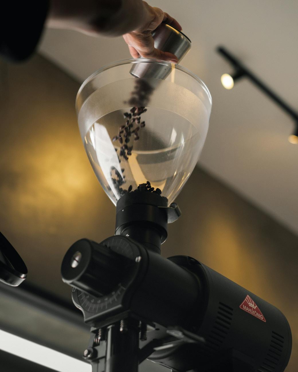 pouring coffee beans into a commercial espresso grinder