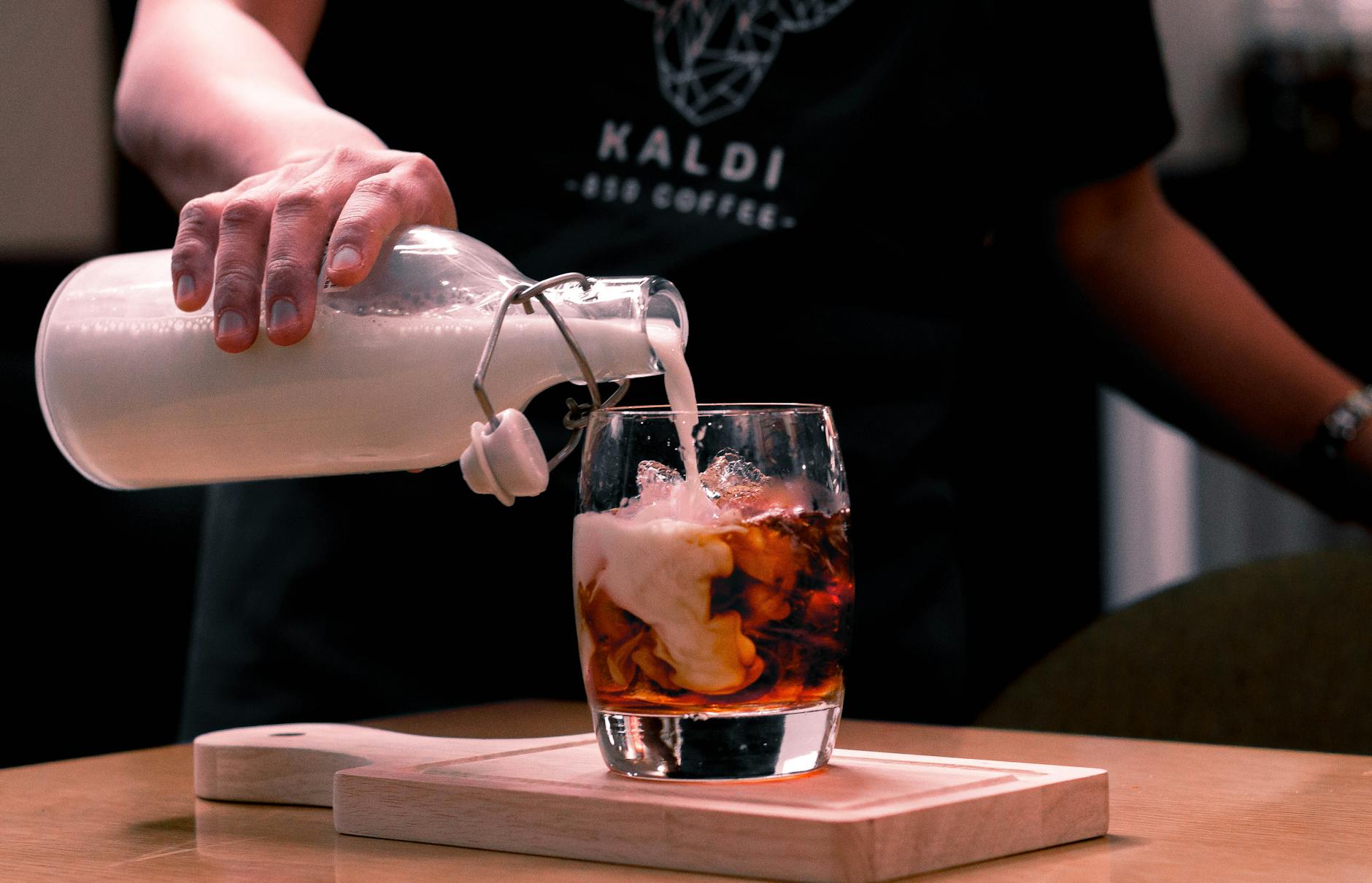 photo of person pouring milk on glass