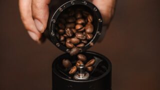 man pouring coffee beans into a grinder