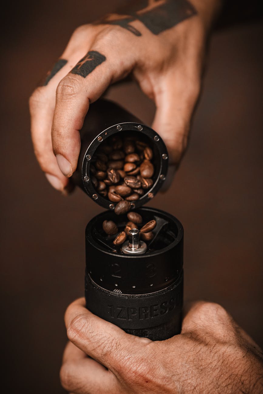 man pouring coffee beans into a grinder