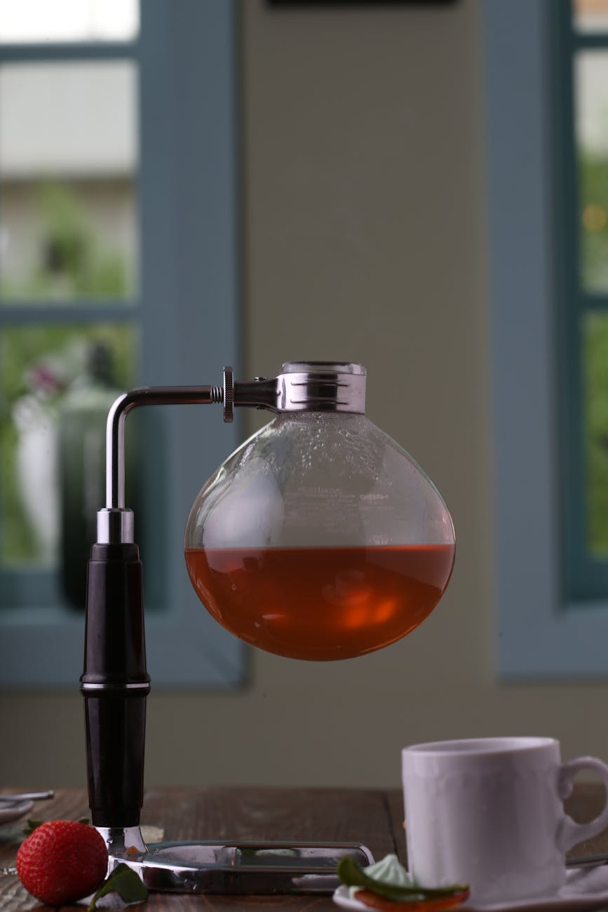 syphon coffee maker beside a white mug